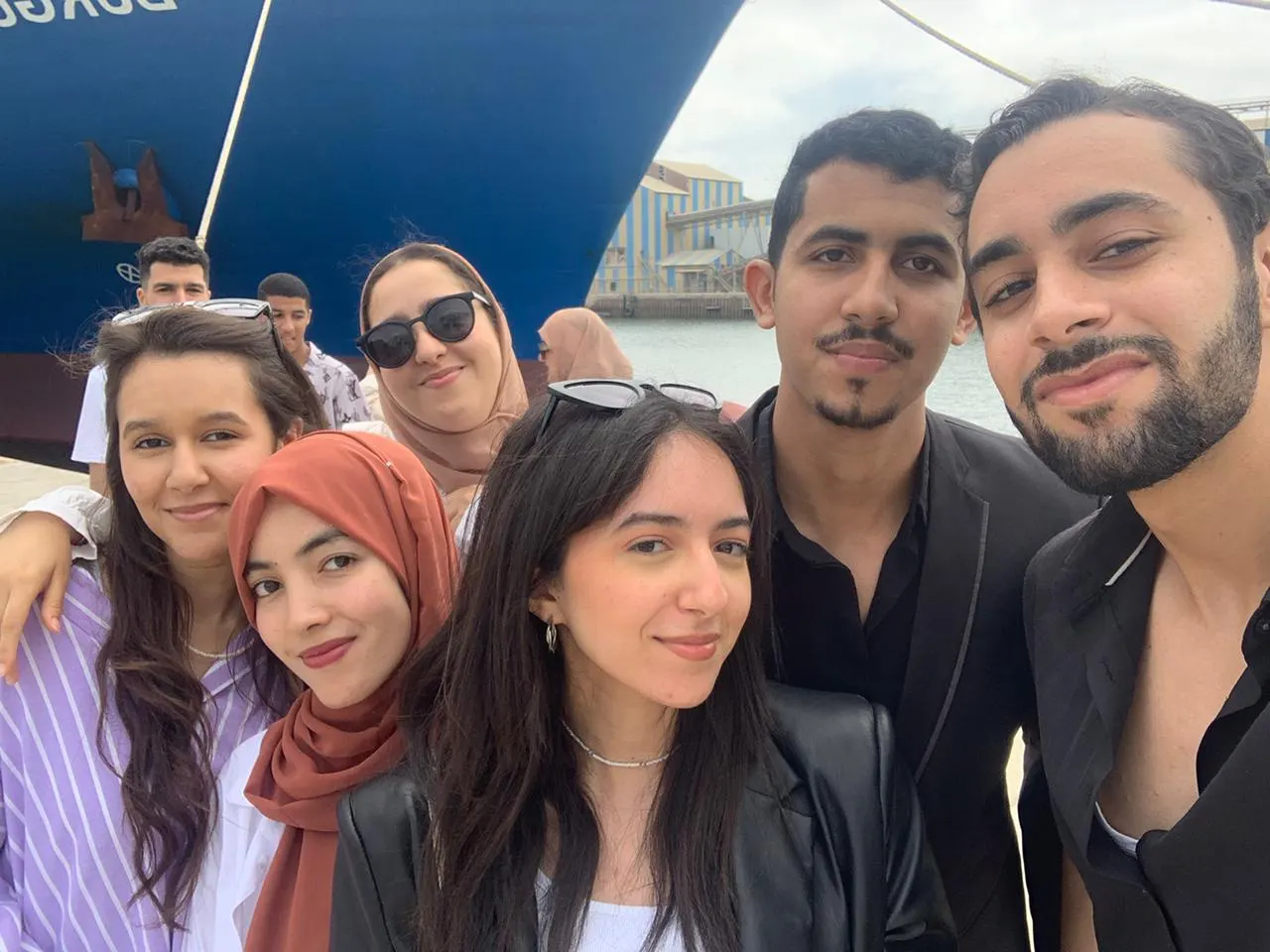 Selfie d'un groupe d'étudiants souriants devant la proue d'un navire